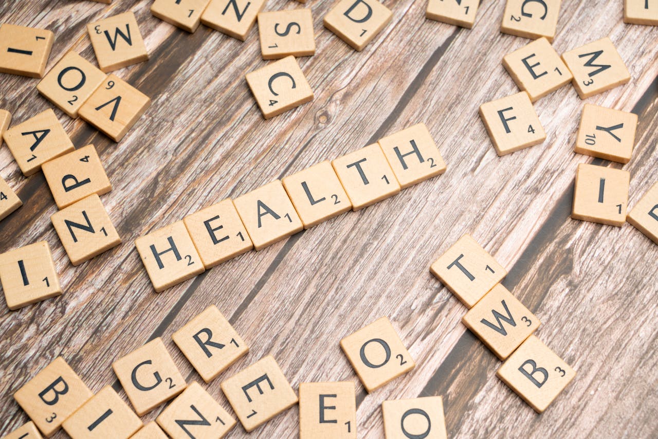 Scrabble tiles spelling 'HEALTH' on wooden surface, symbolizing wellness.