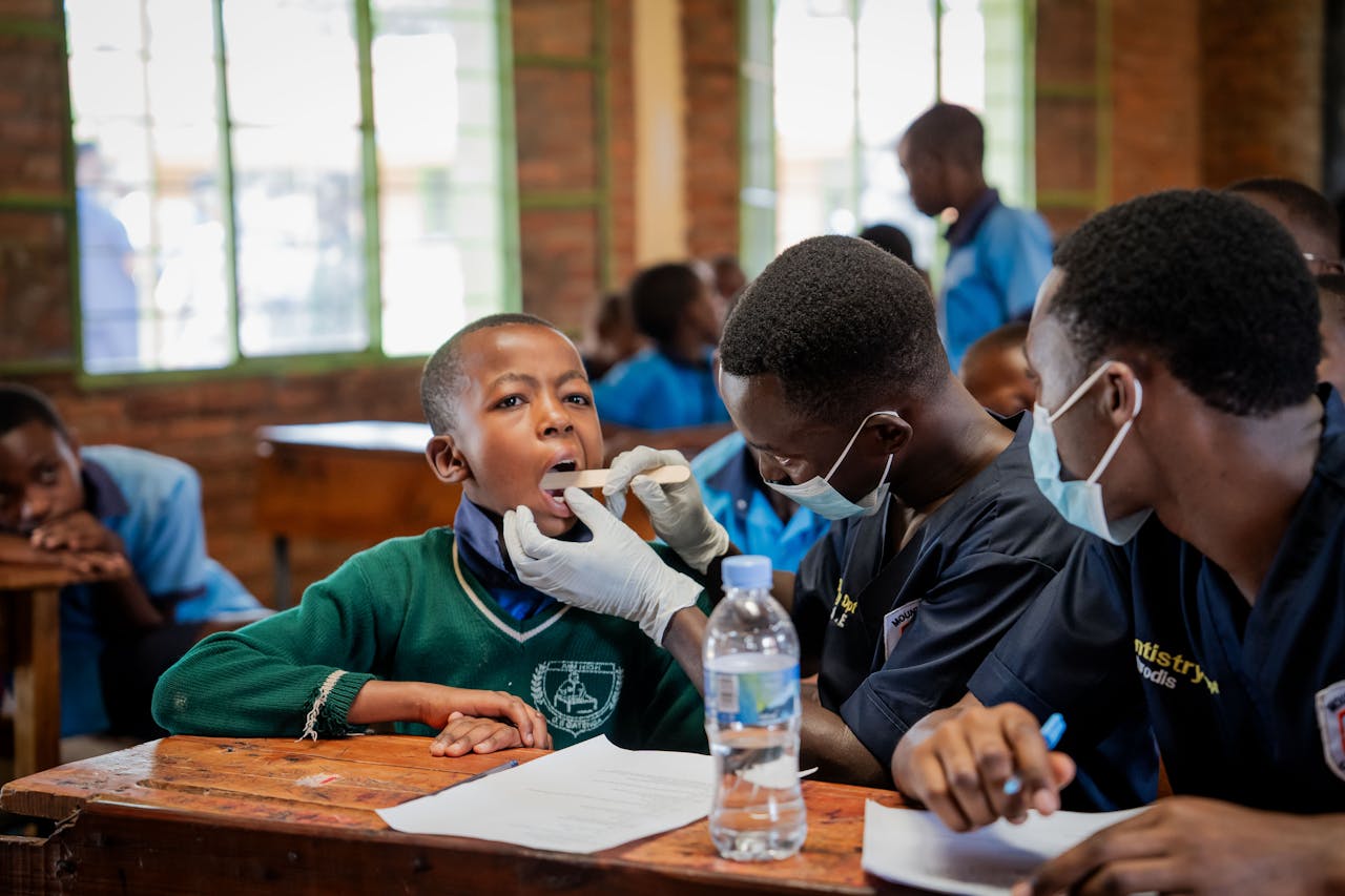 A child receives a dental checkup from a healthcare worker at a community clinic, highlighting preventive care.