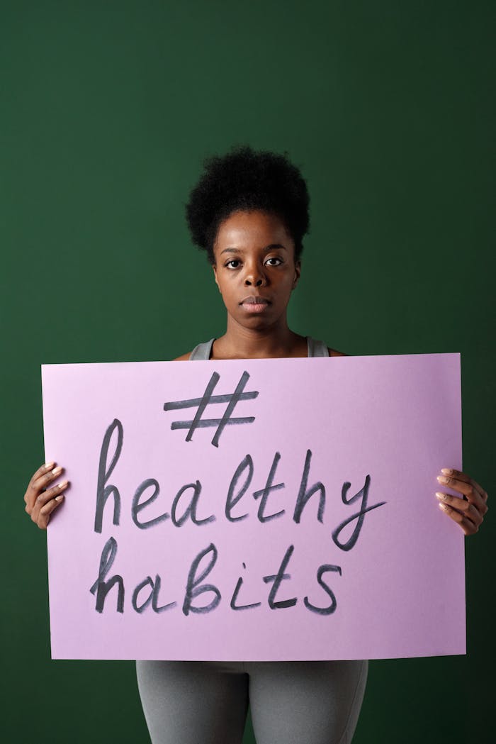 African American woman holding a healthy habits poster, promoting wellness.