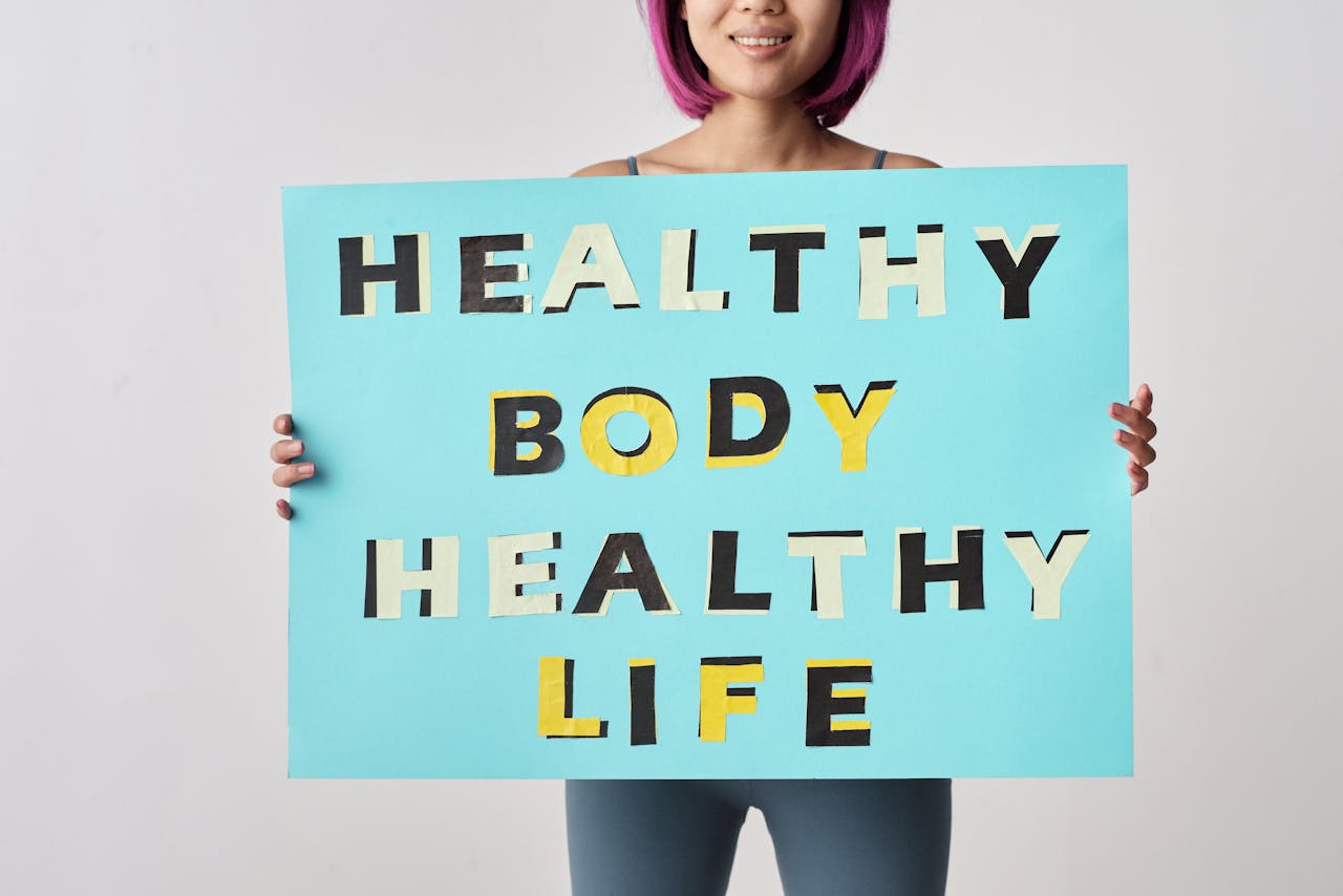 A woman holds a motivational poster advocating a healthy body and life for wellness.