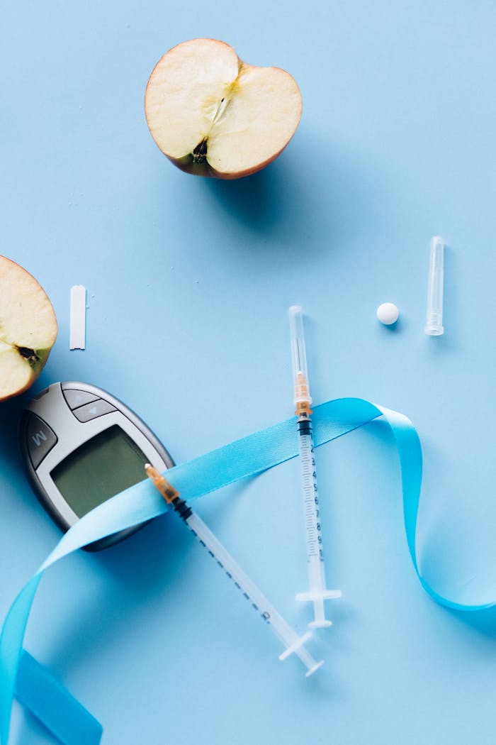 Flat lay of diabetes tools with sliced apple on blue background.