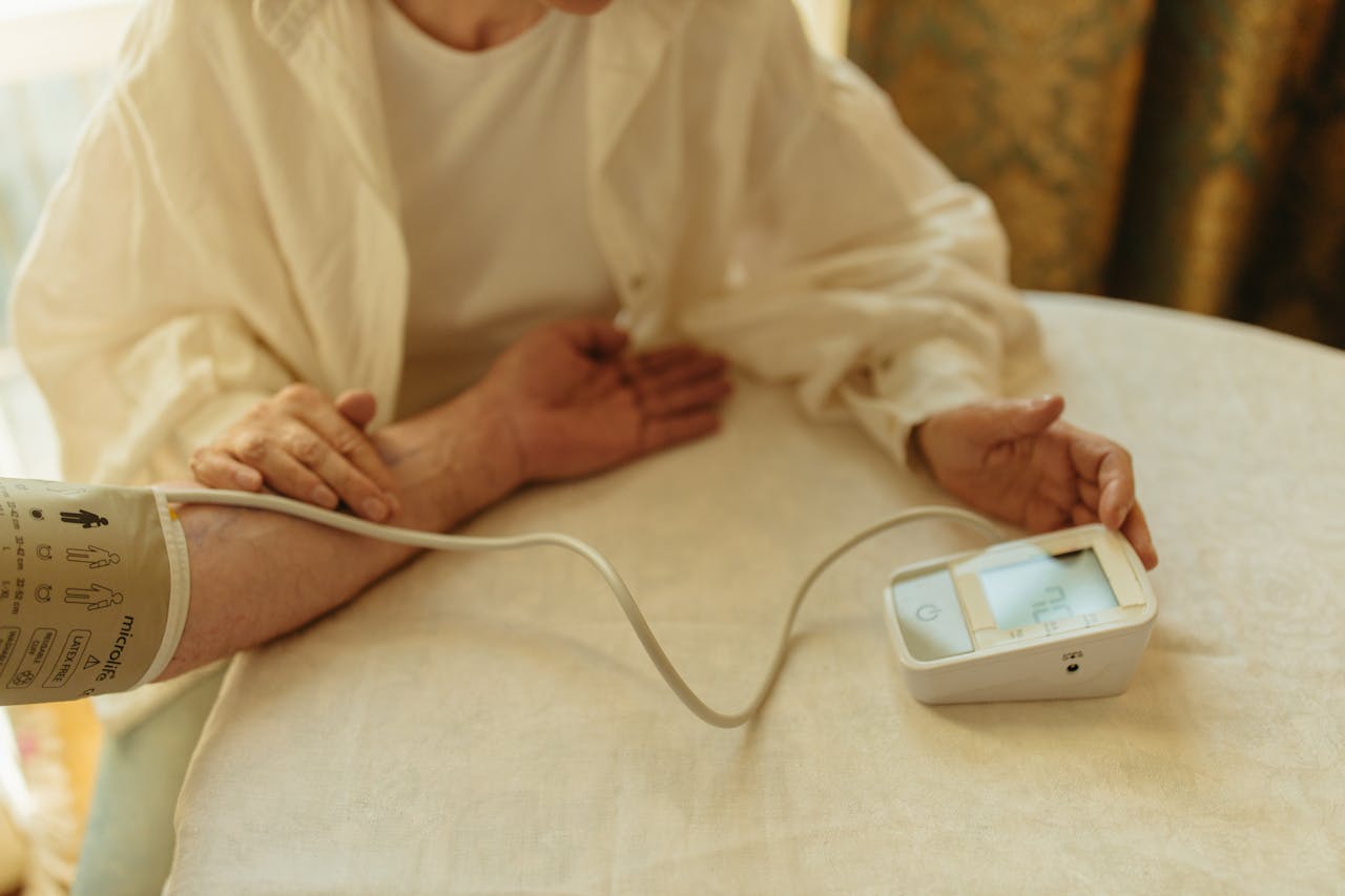 A senior adult checking their blood pressure with a digital monitor at home.